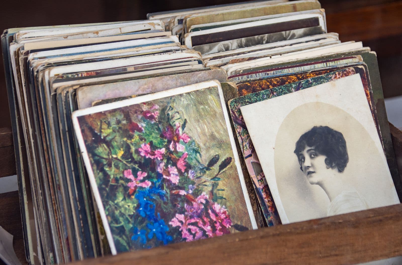 A collection of old postcards and a sepia portrait in a wooden box