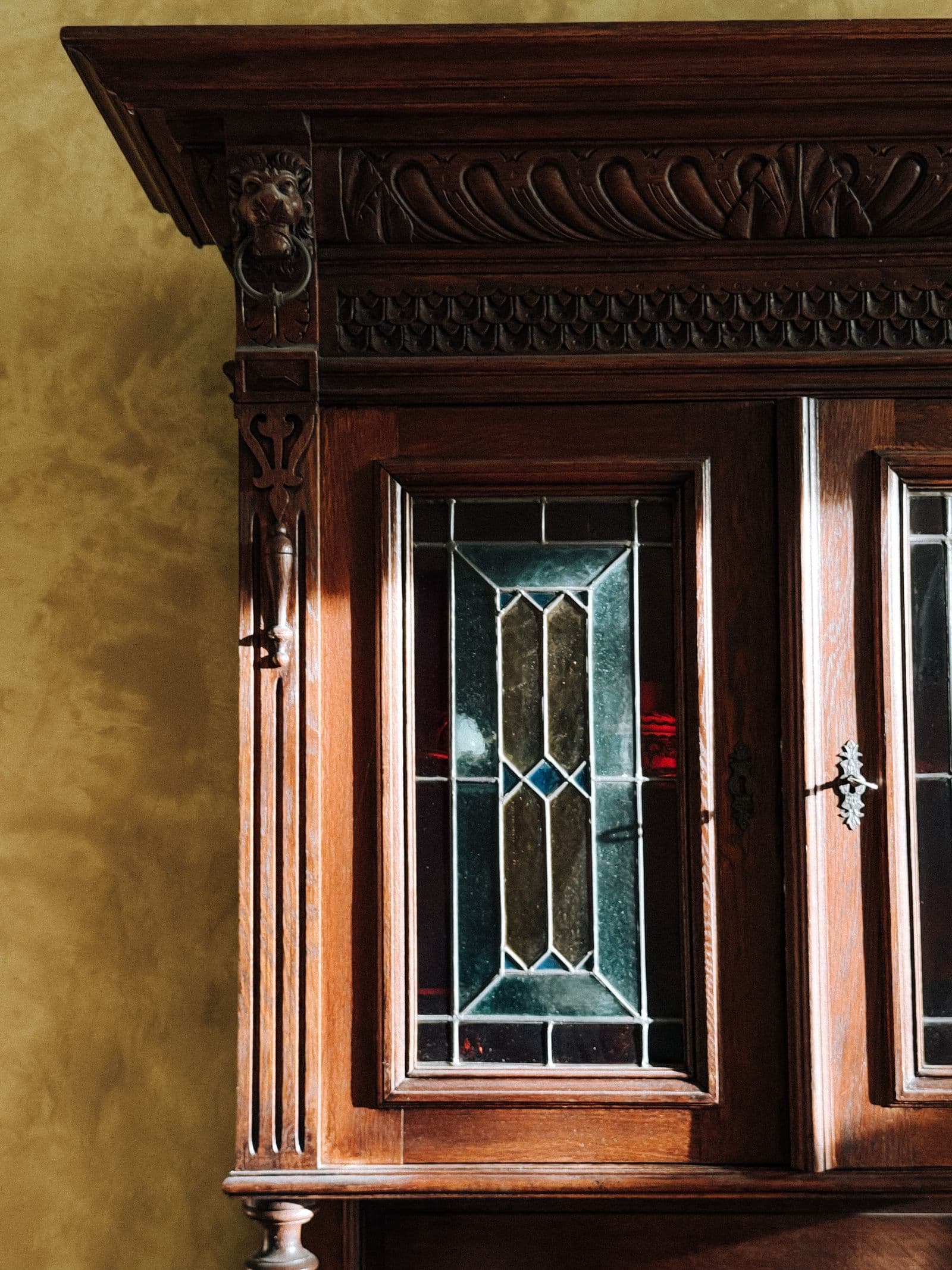 Ornate carved-wood antique display cabinet with stained-glass doors