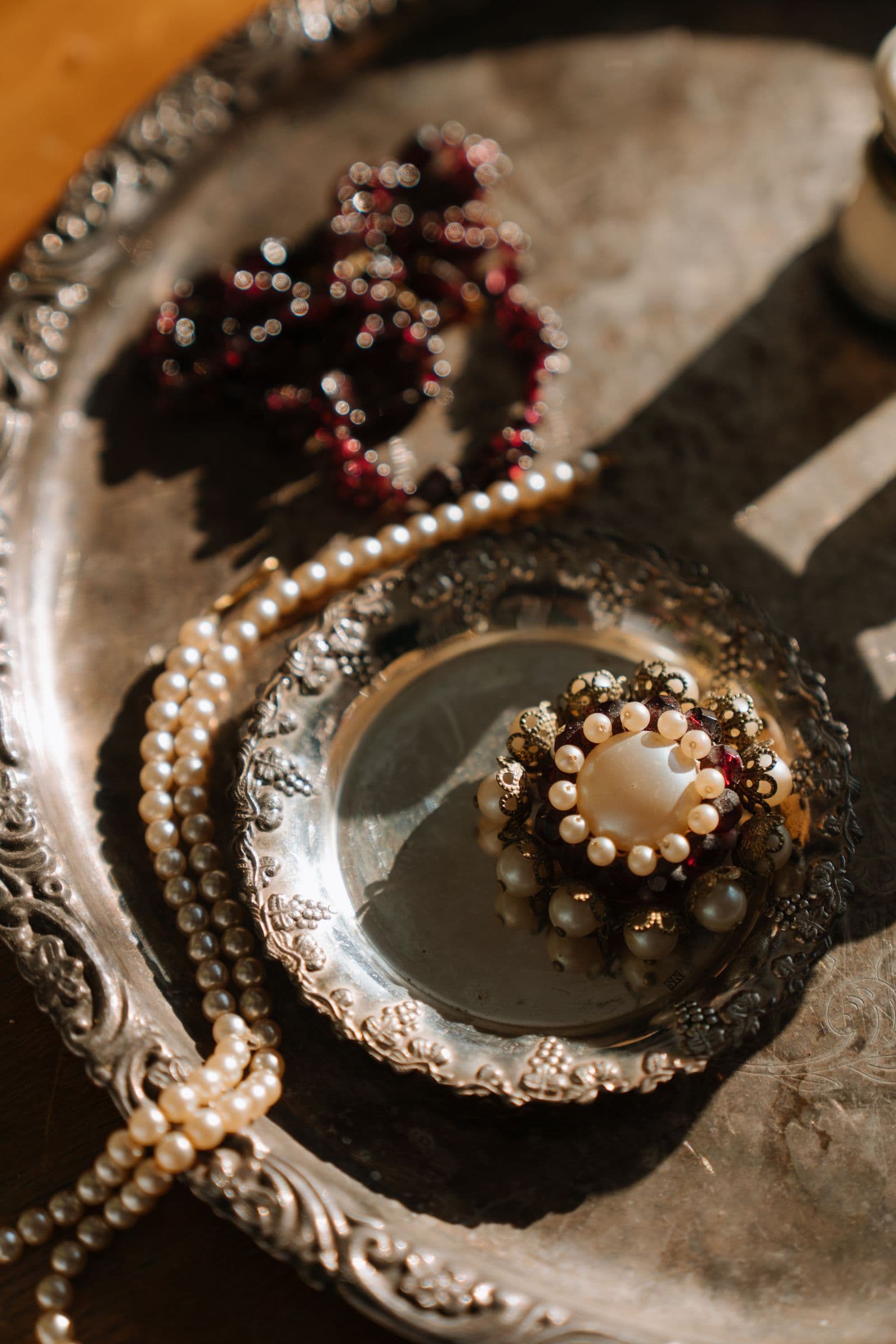 Vintage pearls and an ornate brooch arranged on a silver tray